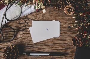 A blank card, glasses and a pen is placed on wood. photo