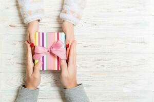 Top view of two people sharing a present on wooden background. Holiday and surprise concept. Copy space photo