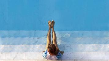 Top view of woman tourist enjoying the relaxation at the refreshing blue crystal clear swimming pool on summer vacation in luxury tropical resort with copy space photo