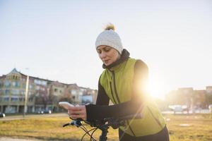 Woman Using Smartphone While Leaning on a Bicycle photo